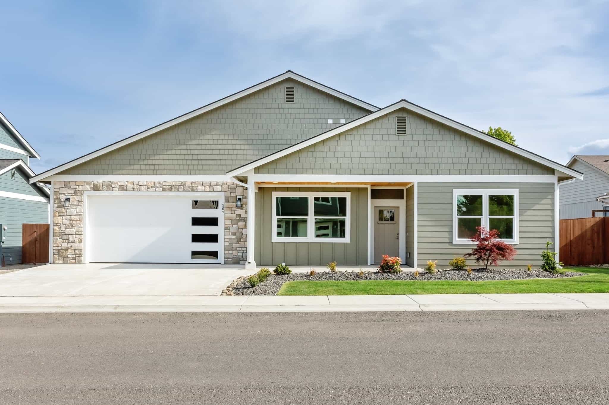 Newly built modern single-story home with gray siding and stone accents.