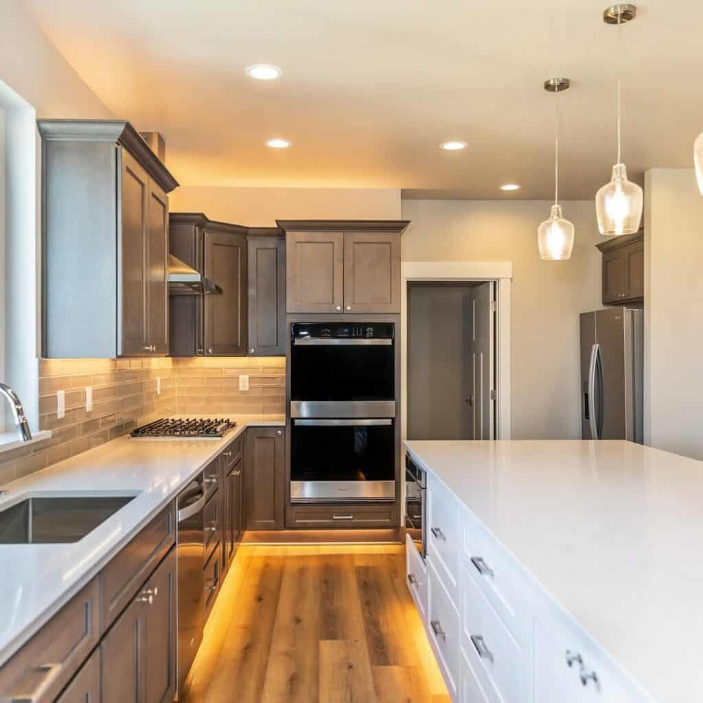 Contemporary kitchen with gray cabinets, white countertops, and pendant lighting.