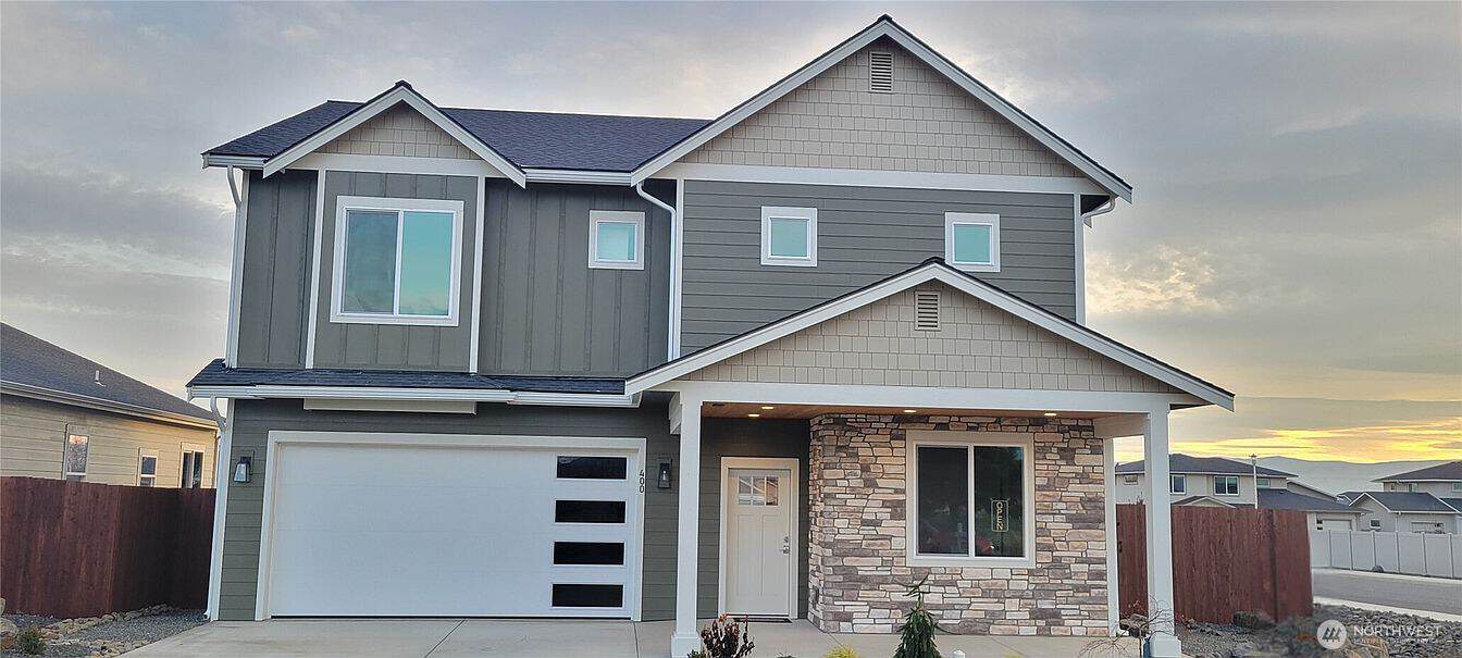 New two-story house with gray siding and stone accents in a suburban neighborhood.