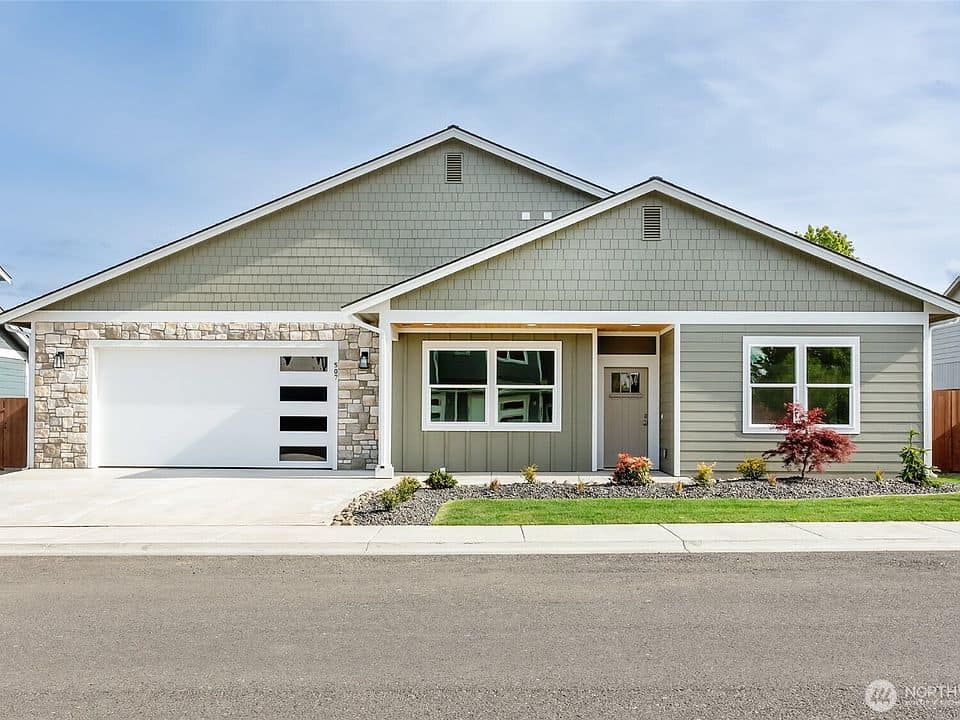 Newly built modern single-story home with gray siding and stone accents.