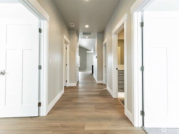 Bright hallway with white doors and wood flooring in a new home.